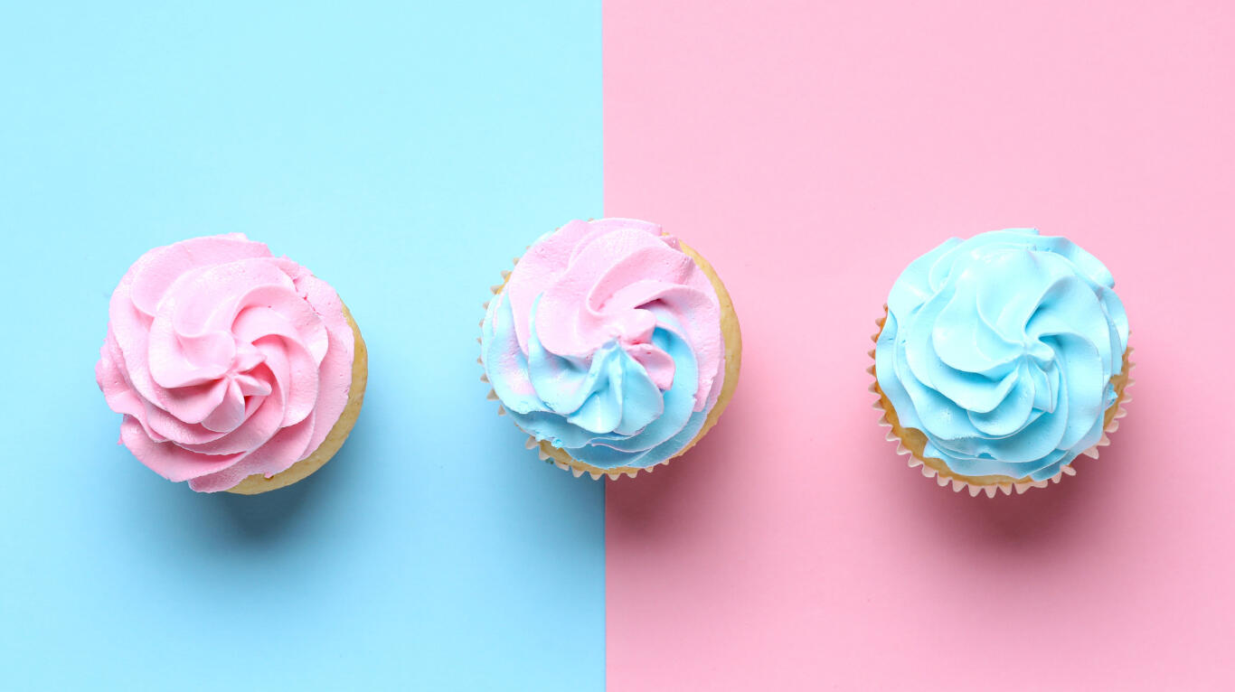 Pink and blue cupcakes for a gender reveal party on a pink and blue background